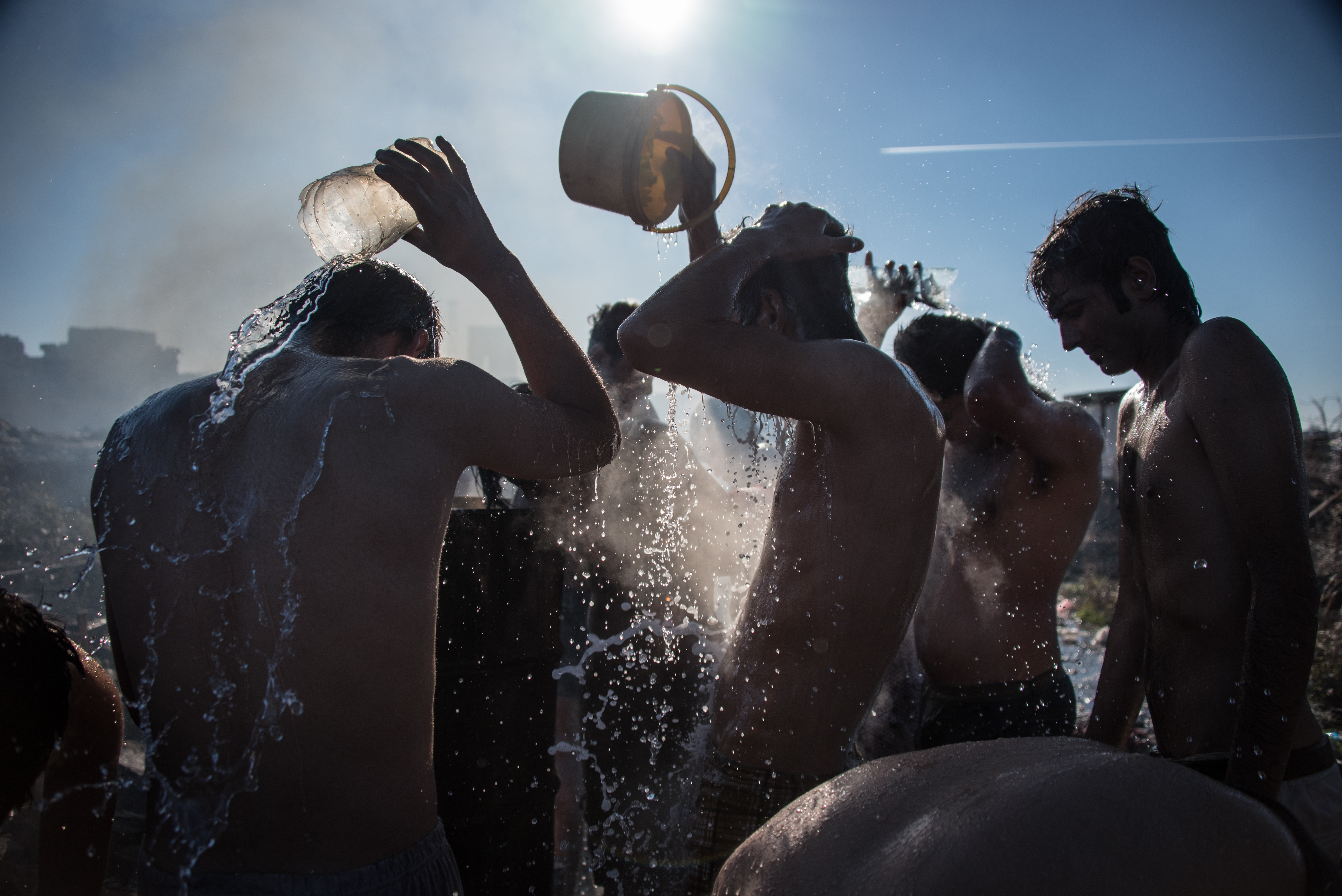 Asylum seekers wash themselves at an outdoor bathing area behind the train depot. Despite rampant skin diseases, the warehouse inhabitants have access to just three “real” showers in a local refugee aid center. (Diego Cupolo)