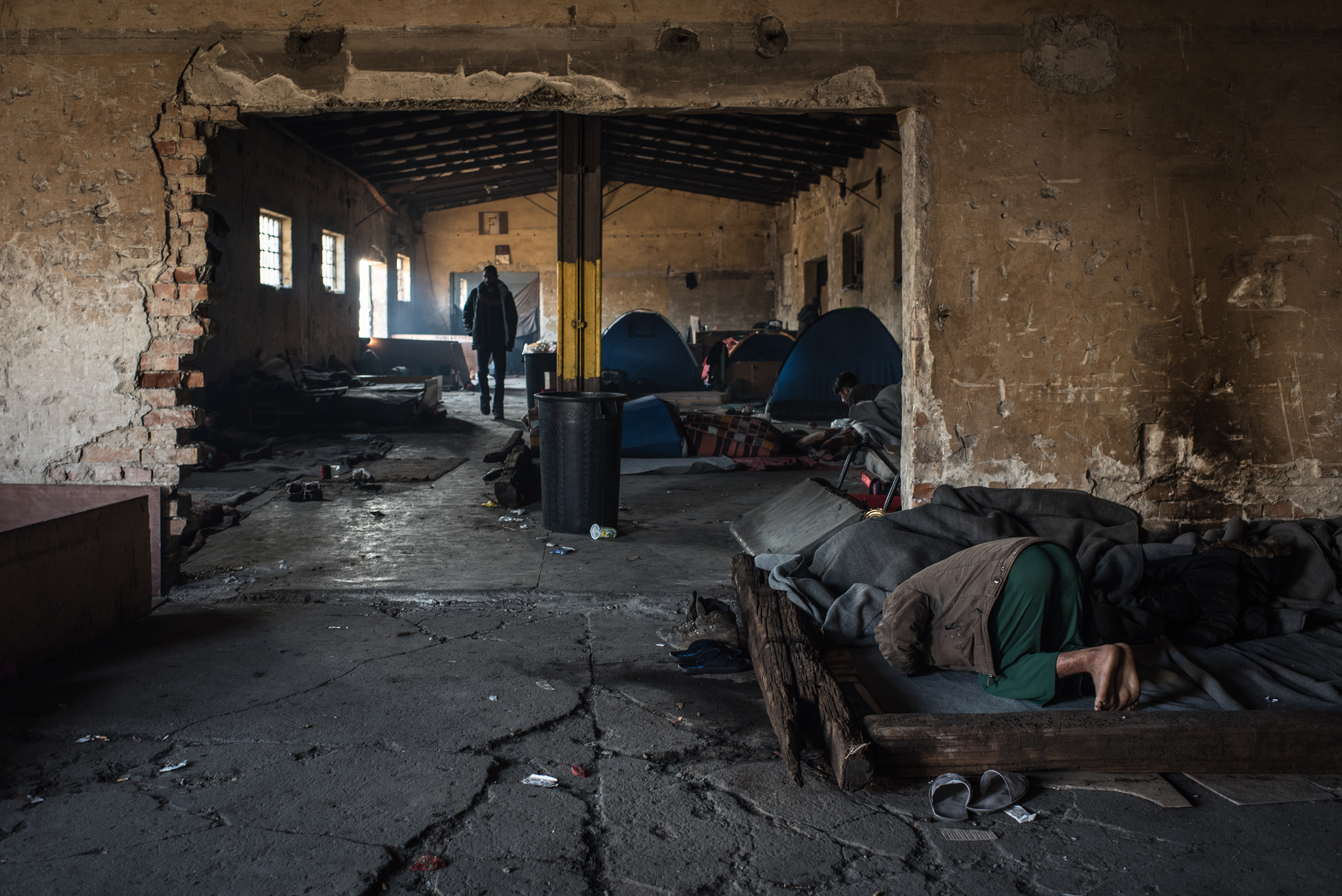 A man prays on his sleeping area inside one of the smaller buildings inside the abandoned train depot complex. (Diego Cupolo)