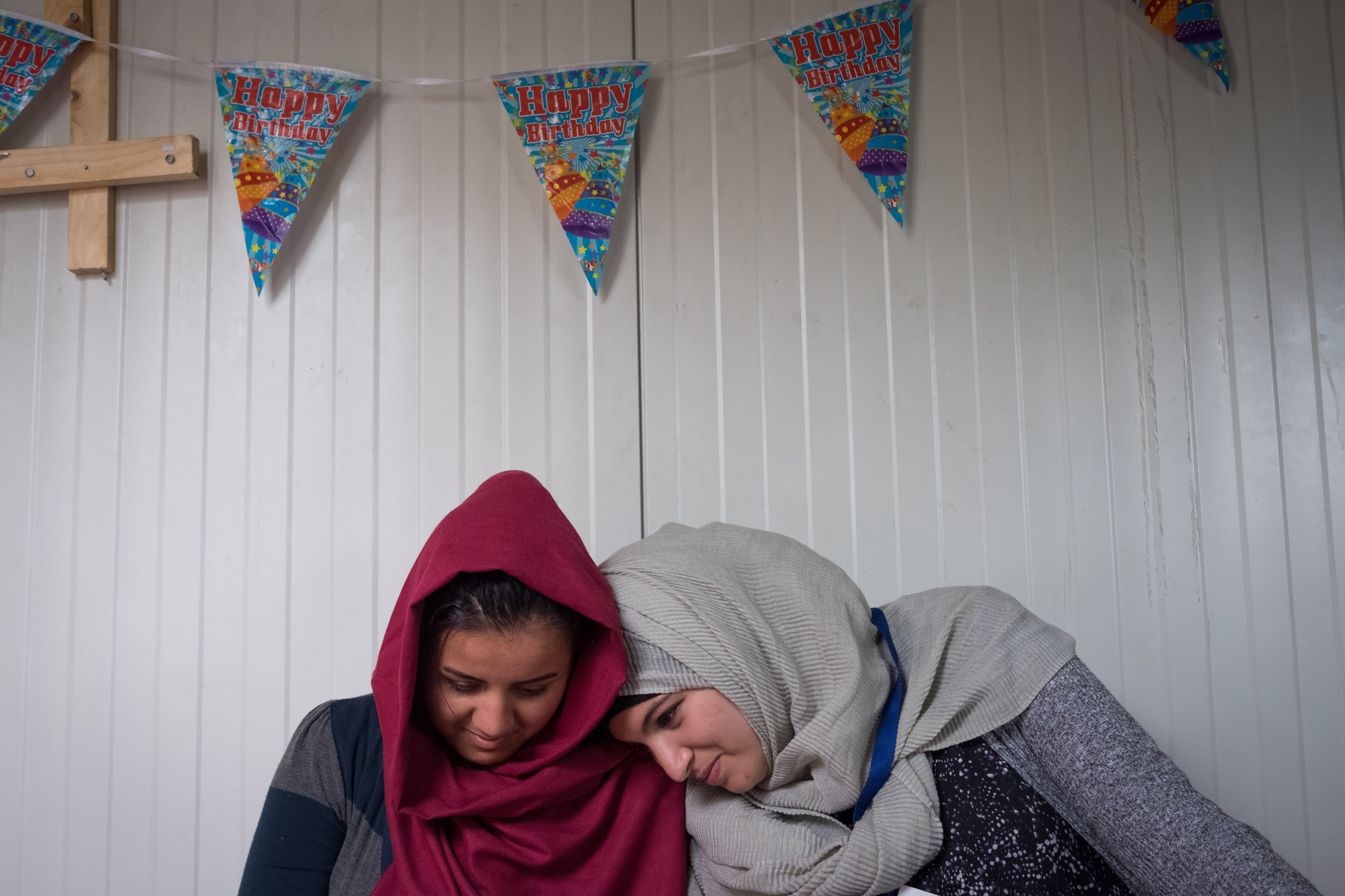 Hafsa Sabr (right) takes a moment to look at a photograph with a Kurdish refugee. Hafsa volunteers at the camp on a daily basis. (Razan Alzayani)