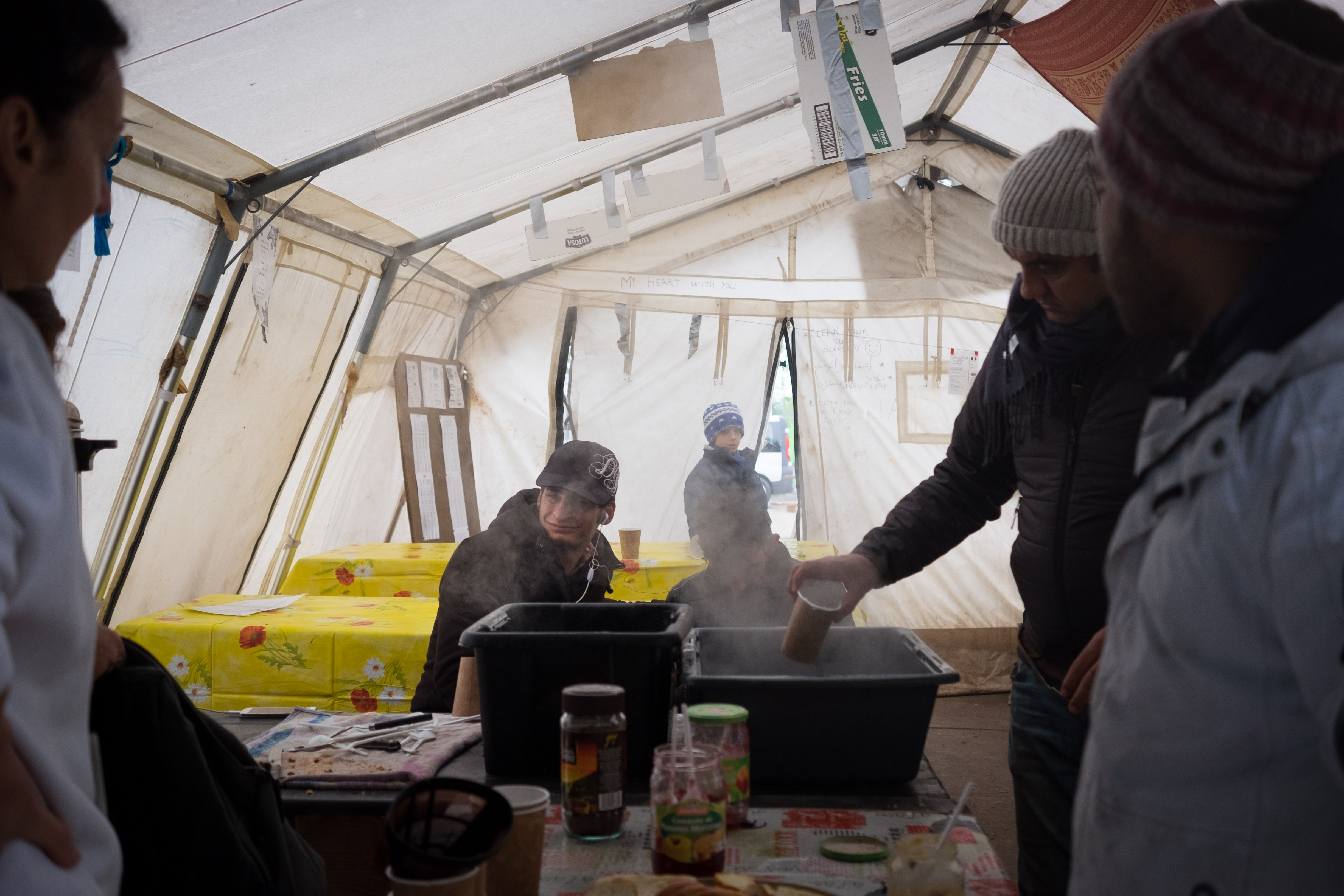 Migrants and volunteers enjoy a break in the tea tent. (Razan Alzayani)
