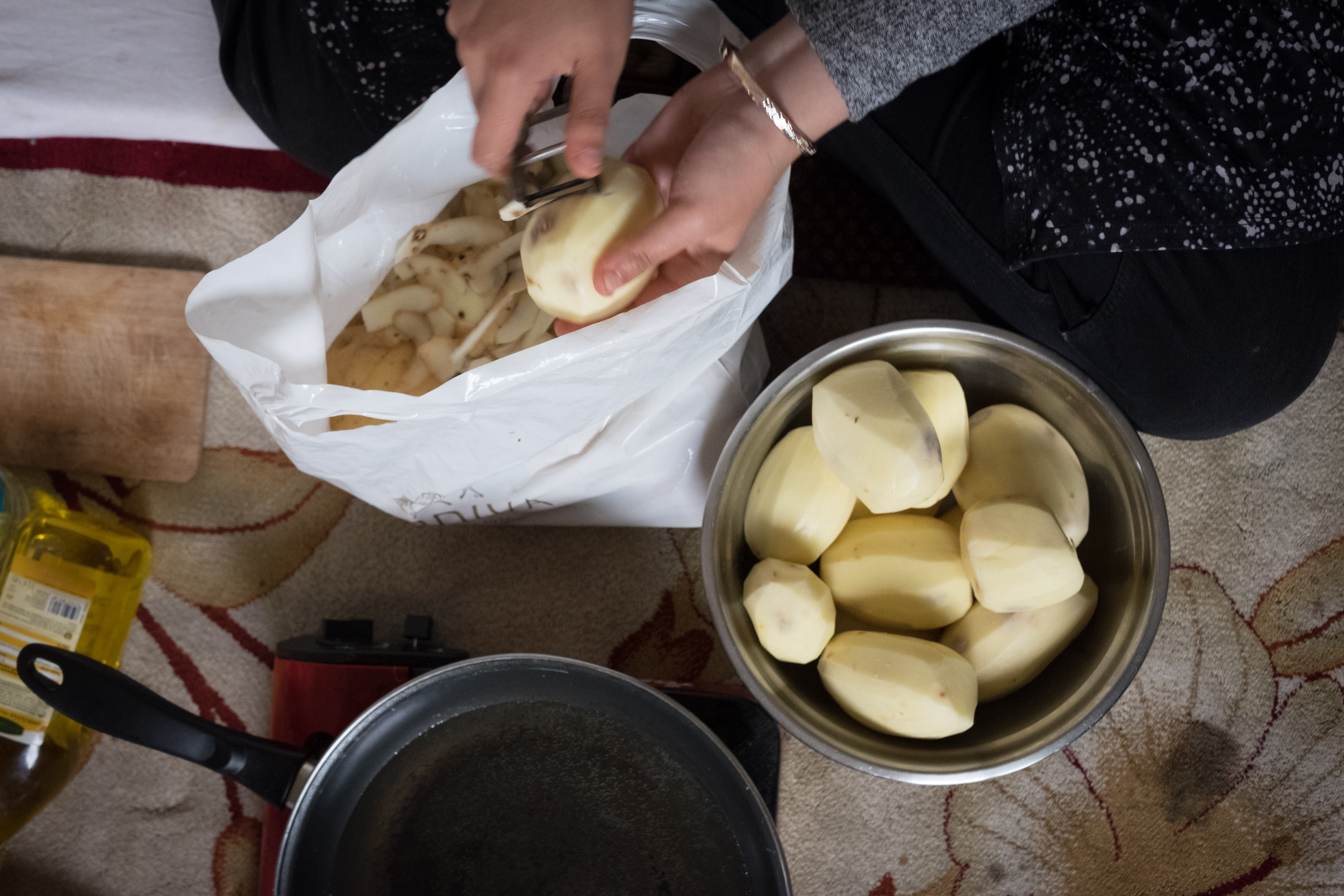 Refugees and local volunteers work together in the kitchen to prepare daily meals. Hafsa, a Dunkirk local, peels the potatoes. (Razan Alzayani)