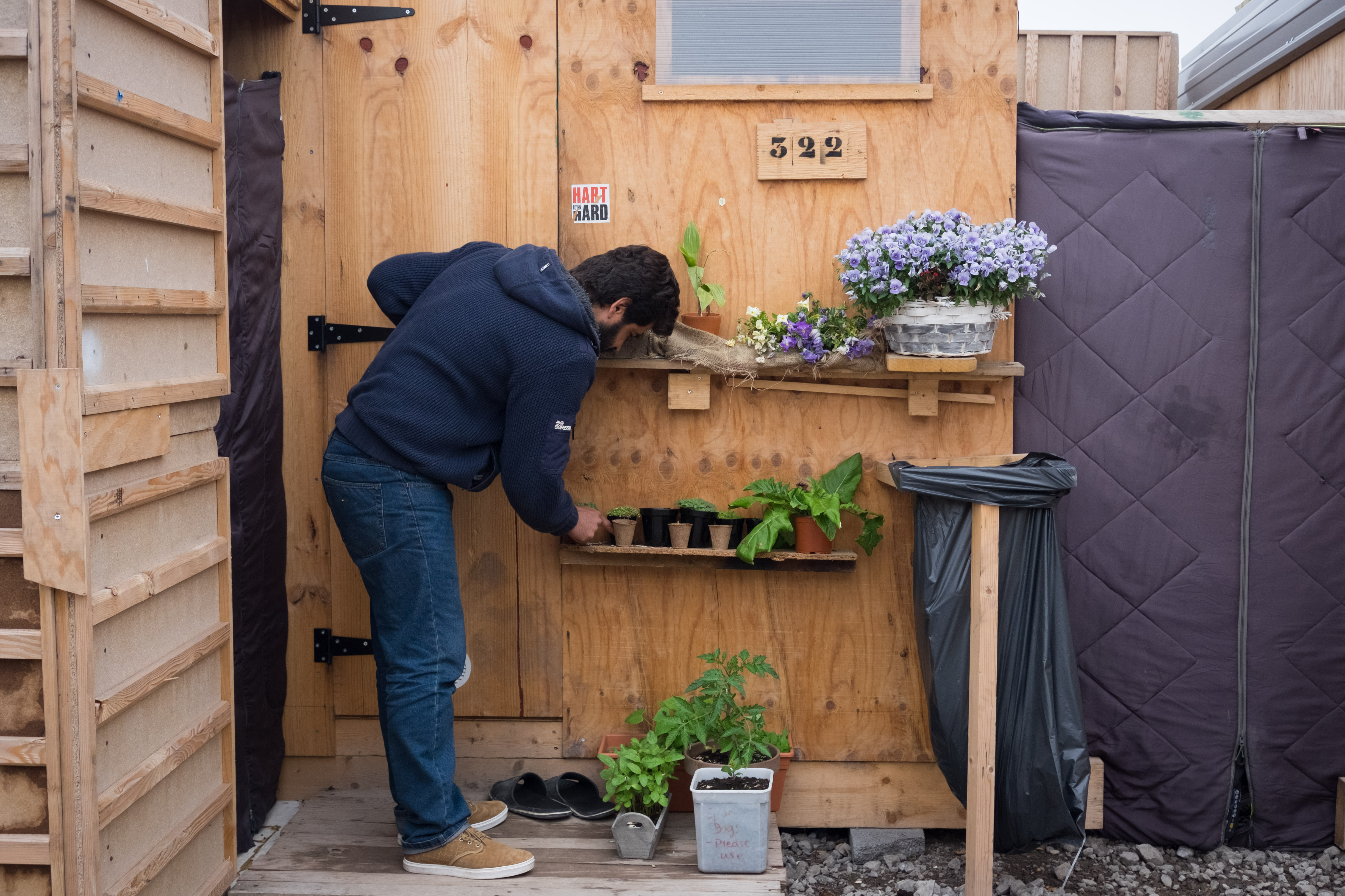 Beshwar Hassan, from Iraqi-Kurdistan, waters his plants outside his cabin. (Razan Alzayani)