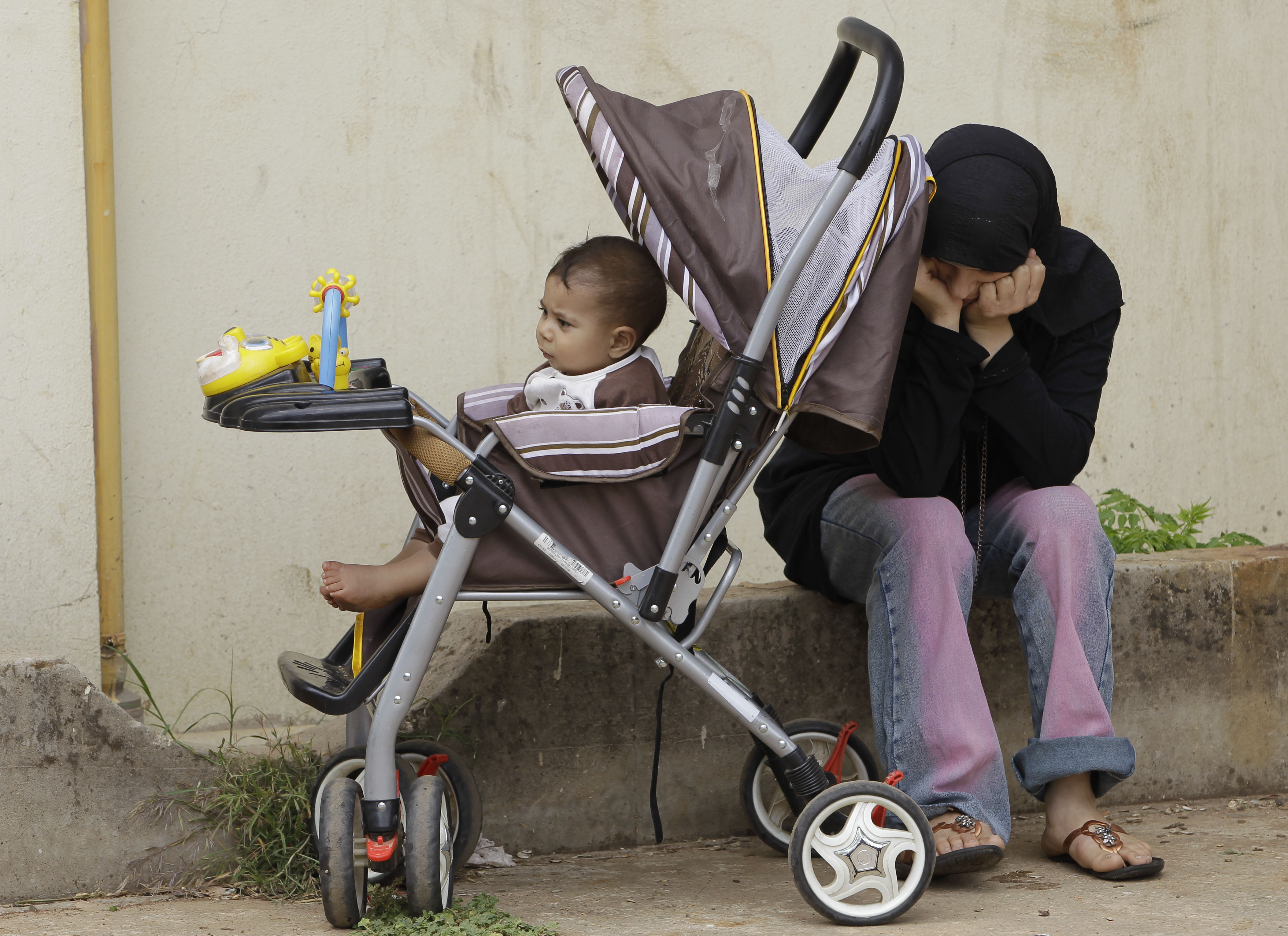 A Syrian refugee woman who fled her home in the Syrian town of Tal-Kalakh, sits next to her baby in a school playground where she lives temporarily with her family and relatives, in Shadra village at the northern Lebanese-Syrian border town of Wadi Khaled, in Akkar, north Lebanon. (AP/Hussein Malla)