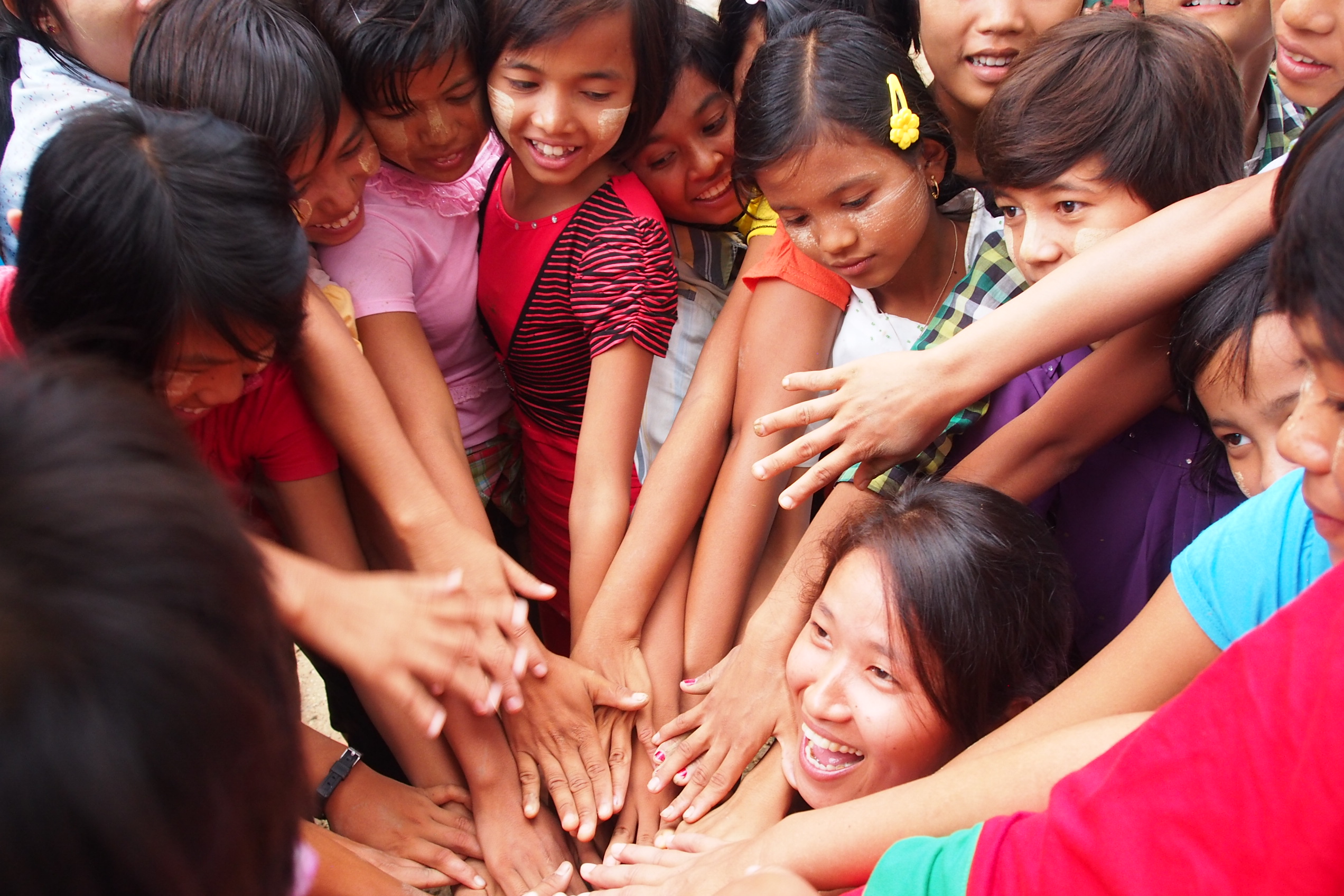 Girls in rural Myanmar do a team cheer with a volleyball coach visiting from Kachin state in the north. Despite active conflict between Myanmar and Kachin rebels, the girls embraced their Kachin guest coach as a leader and role model. (Meg Smith)