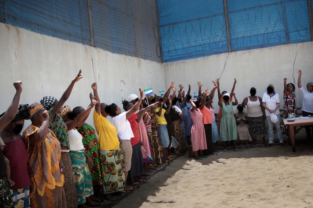 Women raise their hands in solidarity during an event backed by AdvocAid to raise awareness of the importance of women's access to justice. (Tom Bradley/AdvocAid)