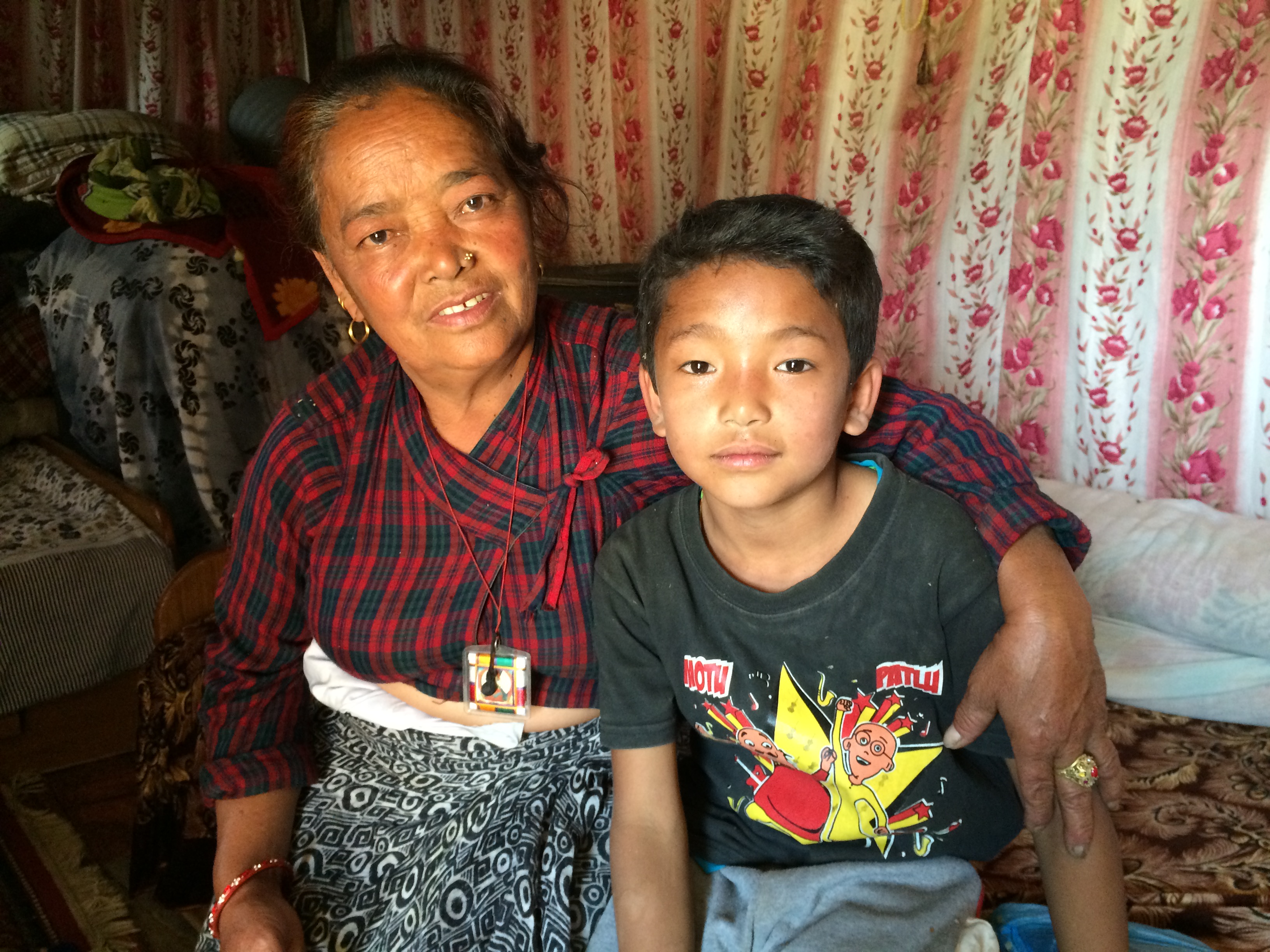 Tamang sits on her bed with her grandson Ayush. (Sonia Narang)