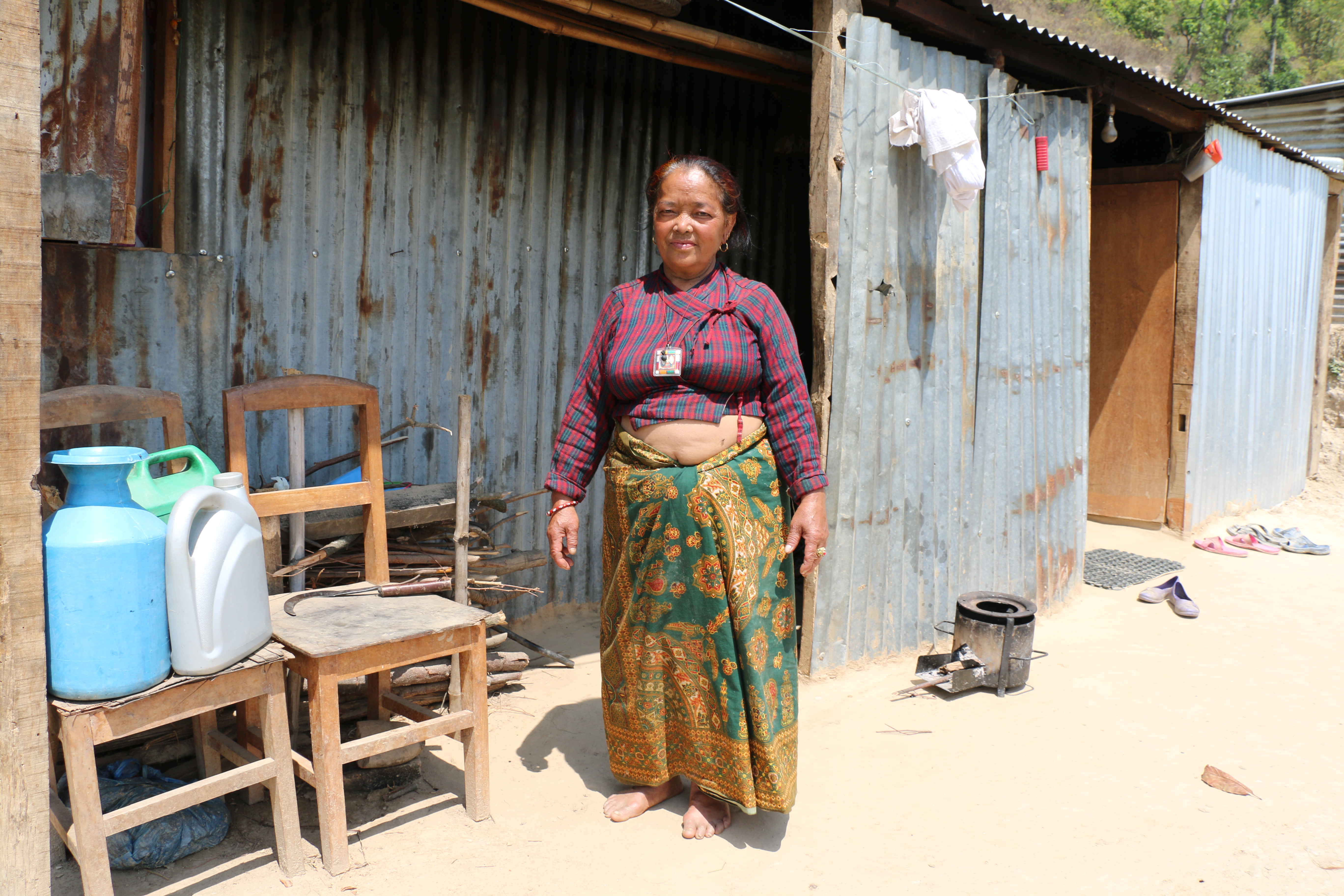 Tamang stands outside the flimsy tin shack she built after her house crumbled in a 7.8-magnitude earthquake last year. (Sonia Narang)